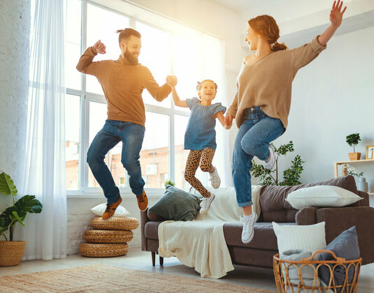 Glückliche Familie tanzt im Wohnzimmer.