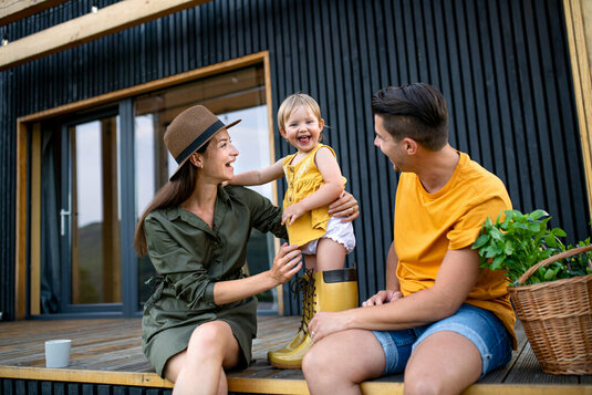 Junge Familie mit kleiner Tochter im Freien, Wochenende in einem Containerhaus auf dem Lande.